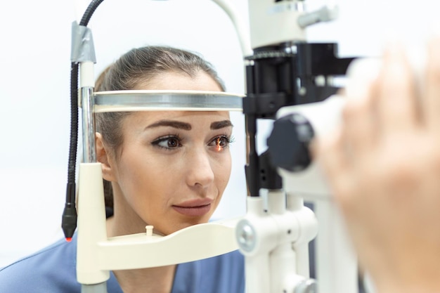Ophtalmologiste avec une patiente lors d'un examen dans une clinique moderne L'ophtalmologiste utilise un équipement médical spécial pour la santé oculaire