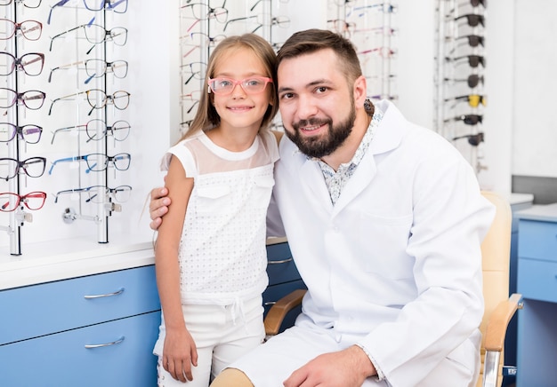 Ophtalmologiste posant avec petite fille à la clinique d'optique