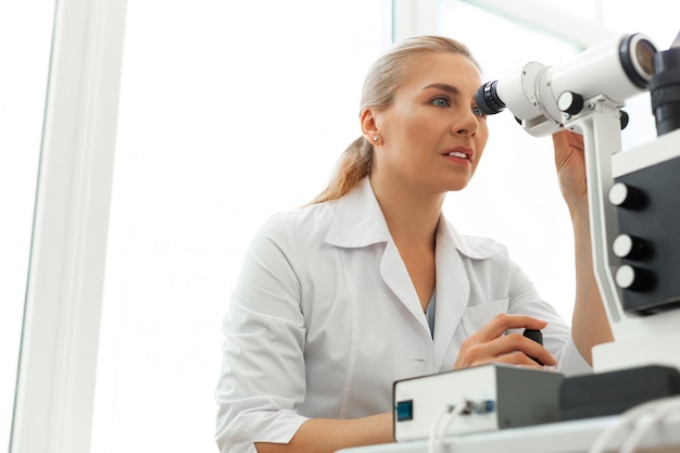 Ophtalmologiste professionnel en uniforme de clinique faire le travail