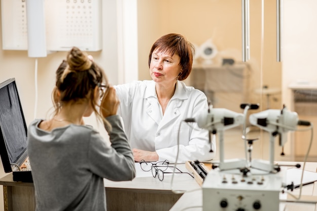 Ophtalmologiste senior femme avec jeune patiente lors de la consultation au cabinet ophtalmologique