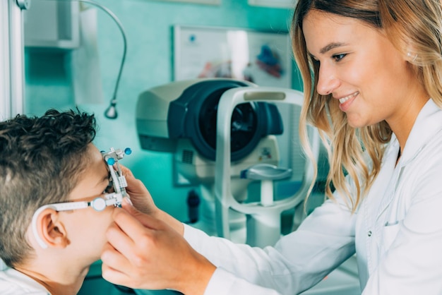 Photo un ophtalmologiste souriant fait un test oculaire d'un garçon.