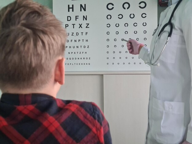 Photo un ophtalmologiste tient un stylo pour vérifier la vision d'un adolescent.