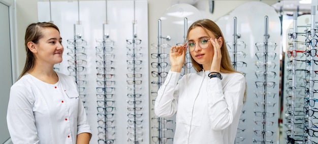 Un opticien aide une cliente à choisir des lunettes dans un magasin d'optique