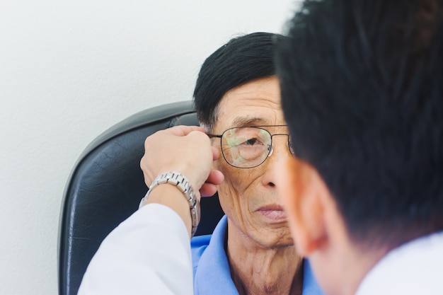 Opticien mâle met des lunettes sur le vieil homme testant son œil