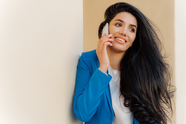 Optimiste femme entrepreneur avec les cheveux noirs ondulés, porte le maquillage