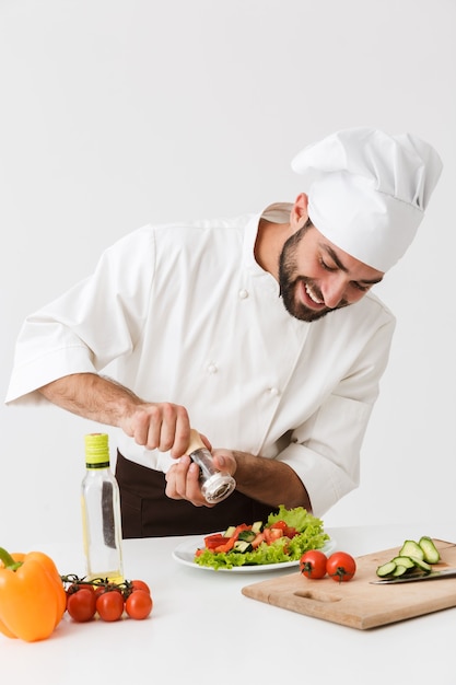 optimiste heureux positif jeune chef en cuisine uniforme avec des légumes frais.