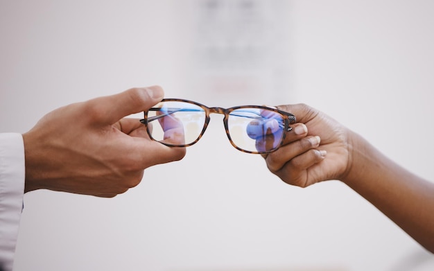 Optométrie des lunettes et mains d'un optométriste et d'une personne pour l'achat de décisions et l'aide à la vision Aide à la consultation et un opticien donnant des montures de lunettes et des lentilles de prescription à un client