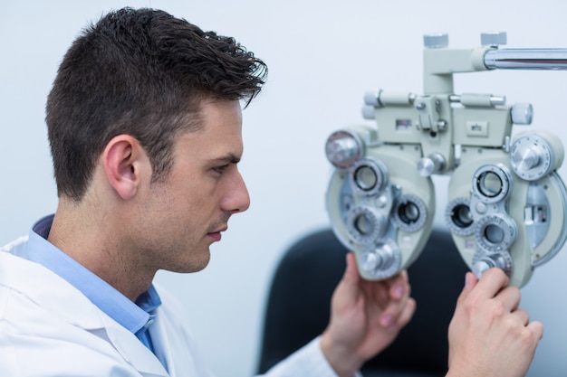 Optométriste attentif ajustant le réfracteur
