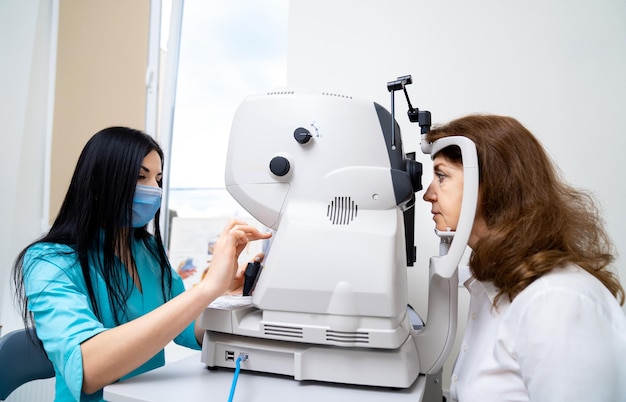 Une optométriste brune diagnostique une femme sur un équipement moderne spécial Clinique à jour pour des yeux sains Gros plan