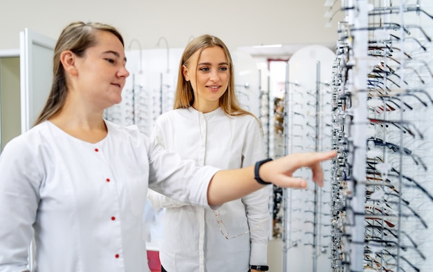 Optométriste féminine. L'opticien est debout avec de nombreuses lunettes en arrière-plan dans un magasin d'optique. Correction de la vue. La femme choisit dioptrique. Consultation en optique. Fermer.