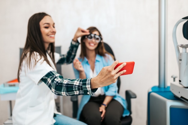 Optométriste féminine prenant une photo de selfie après un examen de la vue.