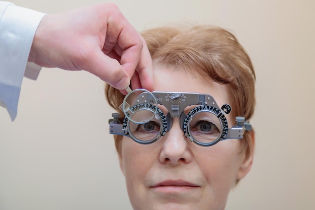 Photo un optométriste vérifie la vue d'une femme adulte à l'aide d'un cadre d'essai