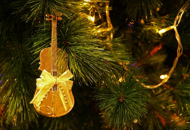 Or brillant en forme de violoncelle avec noeud de ruban ornement de Noël accroché sur l'arbre de Noël