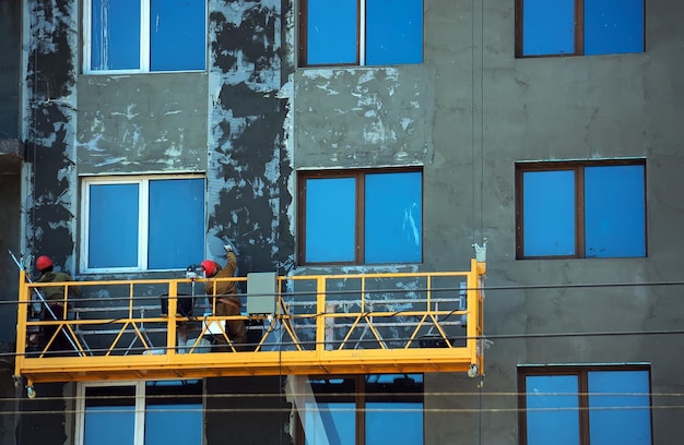 Orange chantier Ascenseur avec les ouvriers contre le mur d'un immeuble en construction Rachie fait la façade de l'immeuble