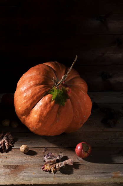 Orange citrouille aux champignons cardoncelli, pommes, noix et feuilles colorées sur de vieilles planches en bois rustiques. Jour d'automne Thanksgiving