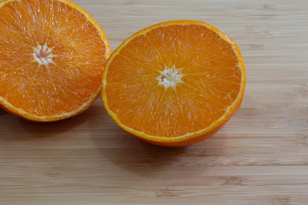 Orange coupée en deux sur la surface du bambou