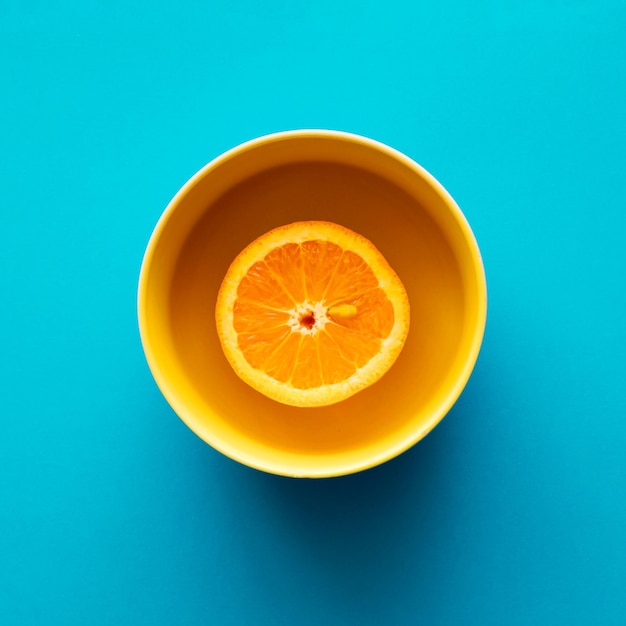 Orange dans un bol de gelée sur un fond bleu à plat