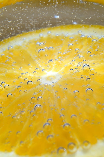 Orange dans l'eau gazeuse avec des bulles. macro.