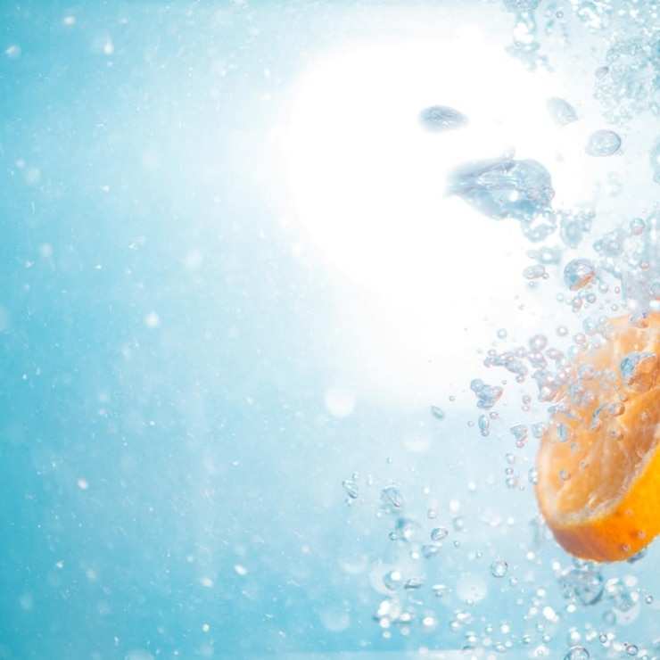 Photo une orange est dans l'eau avec le soleil qui brille dessus