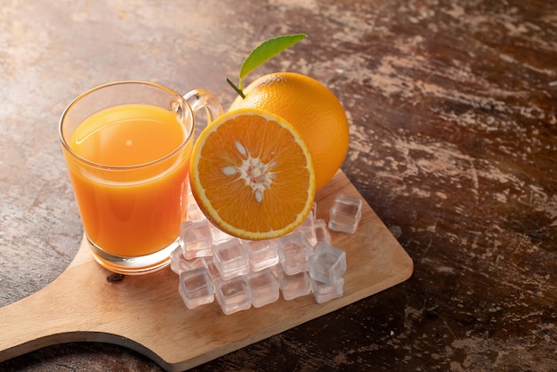 Orange frais et un verre de jus d&#39;orange sur un fond de table en bois