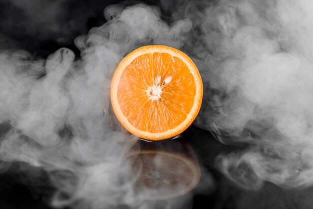 Orange avec de la fumée sur une surface noire