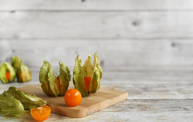 Orange physalis mûre et saine groseille dorée sur planche de bois sur un espace de copie de fond en bois