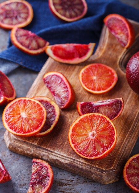 Orange sanguine sur une planche de bois, coupée en quartiers.