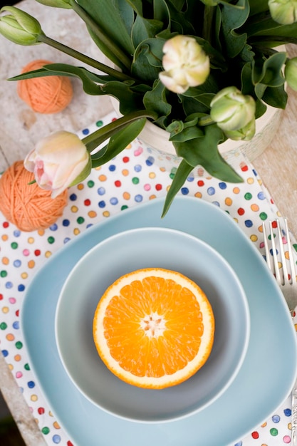 L'orange en tranches lumineuse se trouve sur deux assiettes bleues À proximité se trouve une fourchette un vieux bloc-notes