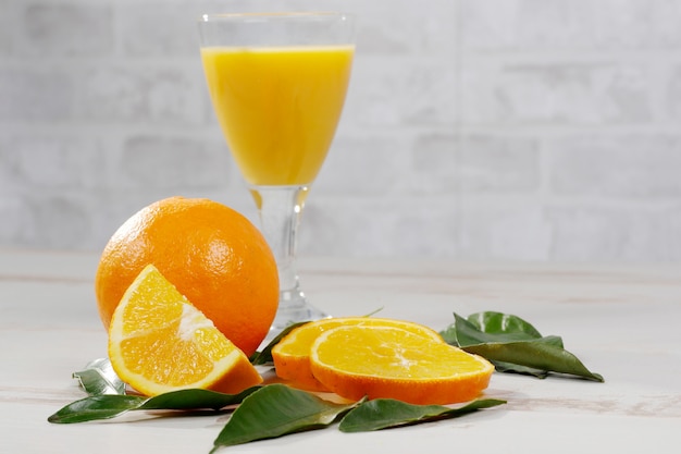 Orange et verre de jus d&#39;orange sur une table en bois blanche