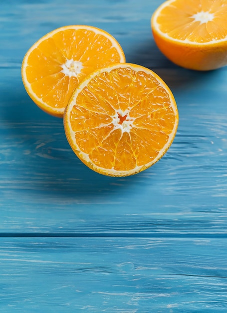 Des oranges biologiques fraîches divisent en deux des fruits sur un fond en bois bleu avec un espace de copie