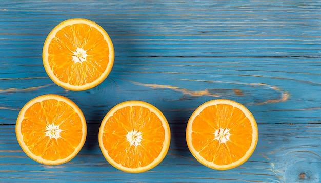 Des oranges biologiques fraîches divisent en deux des fruits sur un fond en bois bleu avec un espace de copie