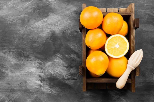 Oranges dans une boîte en bois sur fond noir.