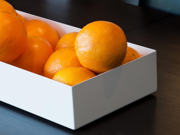 Oranges dans un panier blanc sur table en bois.