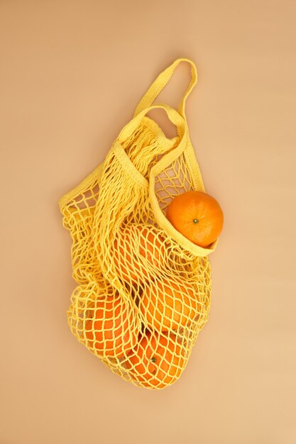 Oranges dans un sac de ficelle sur surface beige