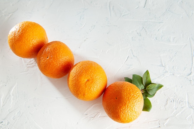 Oranges entières sur fond blanc avec vue de dessus de feuilles vertes