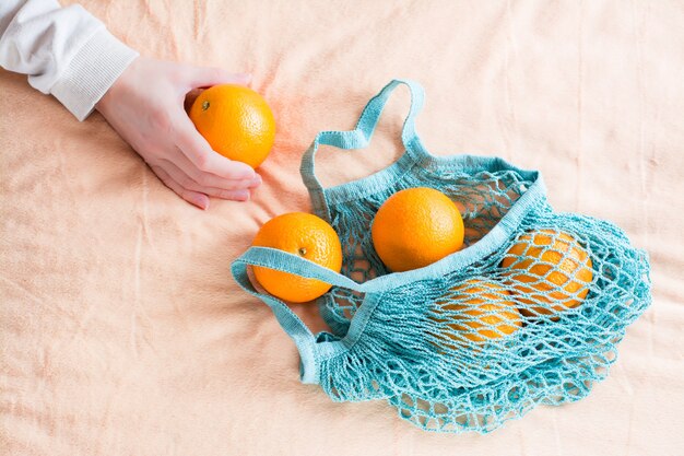 Oranges fraîches dans un sac en filet sur un tissu. Concept zéro déchet