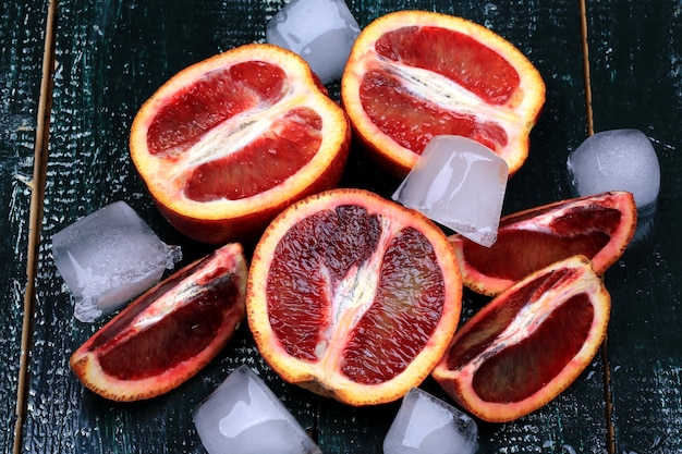 Oranges juteuses rouges avec de la glace sur un fond en bois foncé pour une boisson rafraîchissante d'été
