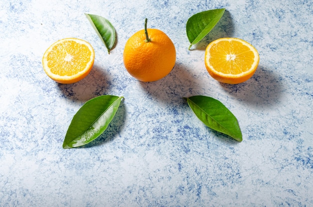 Oranges avec leurs feuilles sur fond bleu