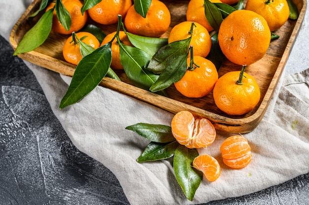 Oranges mandarines fraîches fruits ou mandarines avec des feuilles dans un bol en bois.