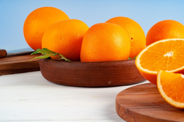 Oranges mûres entières dans un bol en argile sur tableau blanc