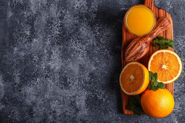 Oranges mûres fraîches et jus sur table en pierre.