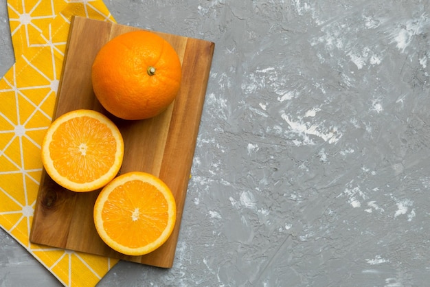 Oranges mûres fraîches sur une planche à découper sur la table vue sur le dessus plat