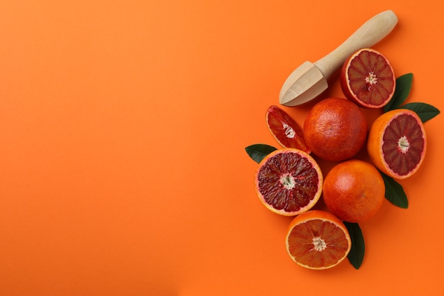 Oranges rouges, feuilles et presse-agrumes sur orange