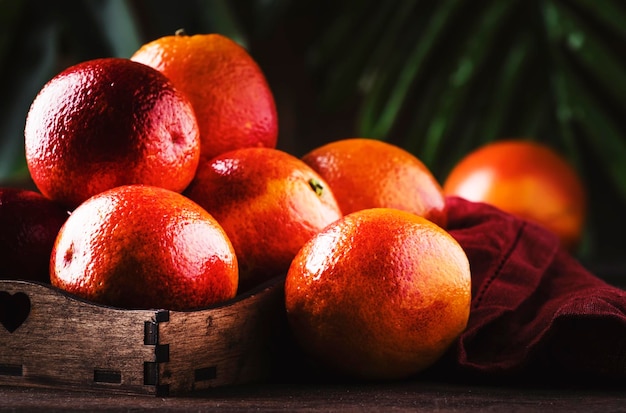 Oranges sanglantes rouges brillantes mûres juteuses dans le bac pour faire un cocktail rafraîchissant sur fond de table en bois rustique mise au point sélective de la vie morte