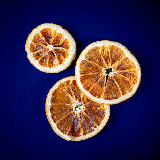 Oranges séchées sur fond bleu foncé. Carré, vue de dessus