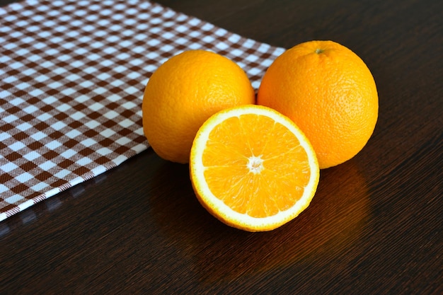 oranges sur table en bois foncé avec nappe sur fond