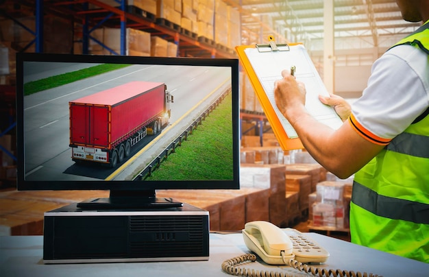 Ordinateur de bureau sur table avec camion semi-remorque à l'écran Travailleurs vérifiant le paquet de stock