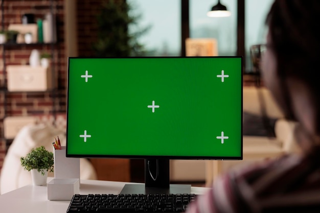 Ordinateur avec écran vert dans le bureau à domicile indépendant, mise au point sélective sur la maquette du moniteur pc. Femme travaillant, assise au bureau du lieu de travail, équipement professionnel des employés avec affichage à clé chroma