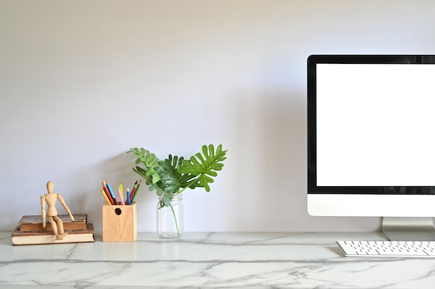 Ordinateur PC sur l’espace de travail avec une tasse de café, un crayon, des livres et une plante sur le bureau.