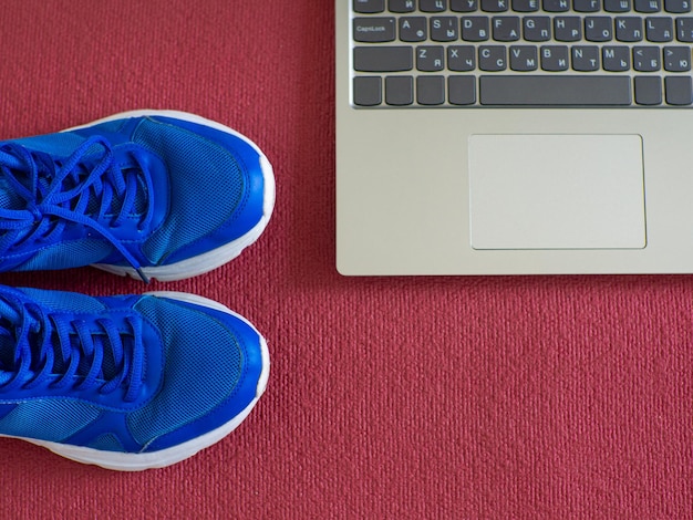 Ordinateur portable de baskets sur un tapis de yoga rouge